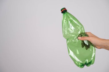 Beyaz arka planda yeşil plastik şişeyi tutan kadının yakın çekimi..