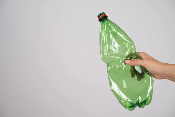 Close-up of female hand holding green plastic bottle on white background. — Stock Photo, Image