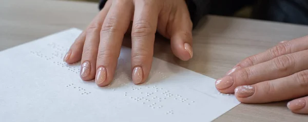 クローズアップの女性は、視覚障害者にテキストを読み上げます。女性は点字コードの紙を手に取る. — ストック写真