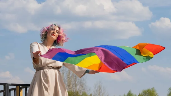Mujer caucásica con cabello rizado con bandera lgbt. Mujer lesbiana sosteniendo una bandera de arco iris al aire libre —  Fotos de Stock