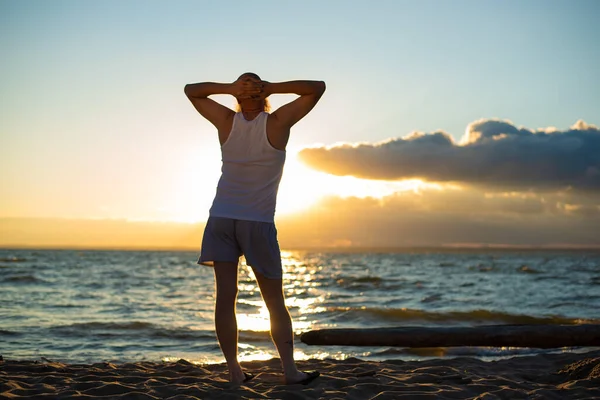 Portrait humoristique d'un homme brutal en T-shirt et boxeur sur la plage au coucher du soleil — Photo