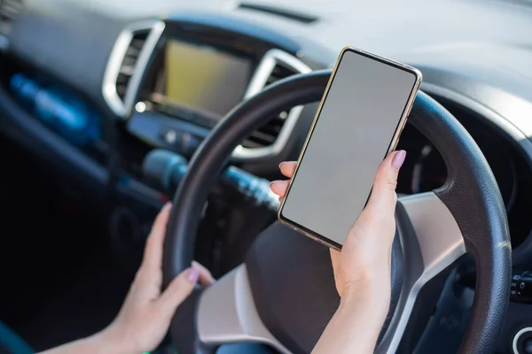 Uma mulher sem rosto usa um telefone celular enquanto dirige um carro. A menina usa a navegação no smartphone — Fotografia de Stock