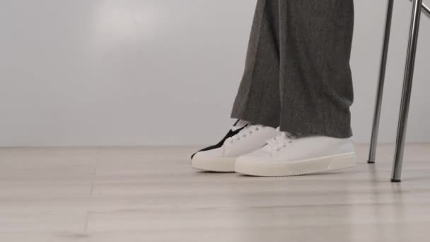 Επιχειρηματίας βγάζει λευκά δερμάτινα αθλητικά παπούτσια και φοράει μαύρα ψηλοτάκουνα παπούτσια. Το κορίτσι αλλάζει παπούτσια πριν τη δουλειά. — Αρχείο Βίντεο