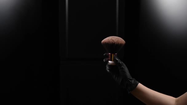Una donna scuote una grande spazzola di polvere con nuvole di polvere su uno sfondo nero. Trattamento dopo abbronzatura istantanea — Video Stock