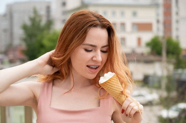 Retrato de jovem bela mulher ruiva sorrindo com aparelho e indo comer cone de sorvete ao ar livre no verão — Fotografia de Stock