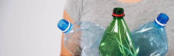 Κοντινό πλάνο του γυναικείου χεριού κρατώντας πράσινο πλαστικό μπουκάλι σε λευκό φόντο. — Φωτογραφία Αρχείου