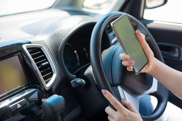 Uma mulher sem rosto usa um telefone celular enquanto dirige um carro. A menina usa a navegação no smartphone — Fotografia de Stock