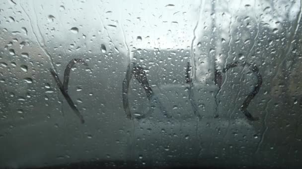 Rain inscription on the fogged windshield of the car. — Stock Video