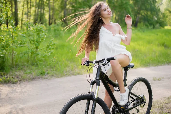 Jeune femme sexy avec de gros seins monte un vélo dans la forêt par une chaude journée d'été — Photo