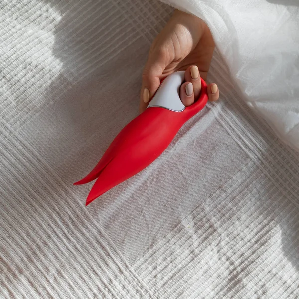 A faceless woman lies in bed under a blanket holding a clitoral vibrator. The girl masturbates — Stock Photo, Image