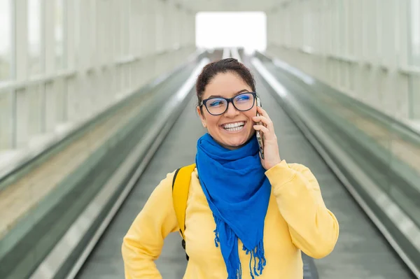 Mujer feliz se para en un viajero y habla en un teléfono celular —  Fotos de Stock