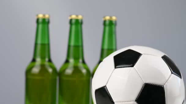 Un pallone da calcio sta girando accanto a tre bottiglie di birra su uno sfondo bianco — Video Stock