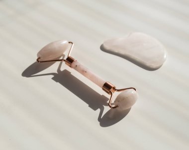 Beyaz bir masada pembe guache kazıyıcı ve silindir. Kendine masaj malzemesi ve yüz ve boyun için cilt bakımı.