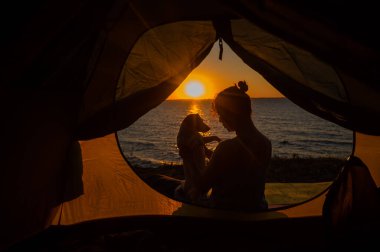 Gün doğumunda bir kadın ve bir köpek turist çadırında. Evcil bir hayvanla kamp yapmak.