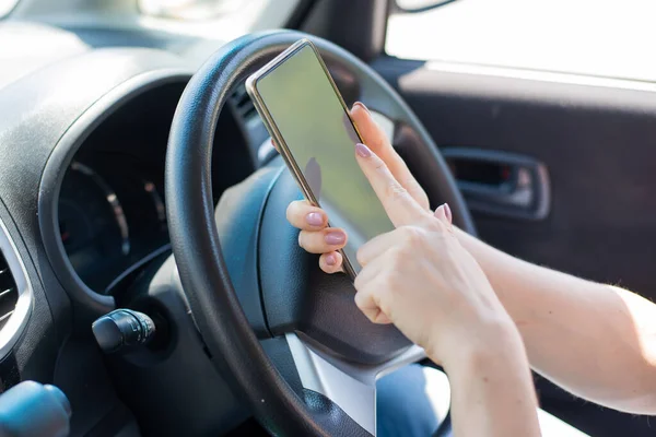 Uma mulher sem rosto usa um telefone celular enquanto dirige um carro. A menina usa a navegação no smartphone — Fotografia de Stock