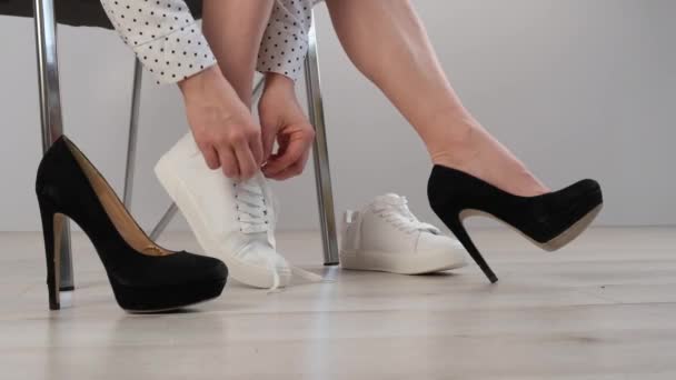 Obchodní žena si sundá bílé kožené tenisky a nasadí si černé vysoké podpatky. Dívka se před prací převlékne. — Stock video