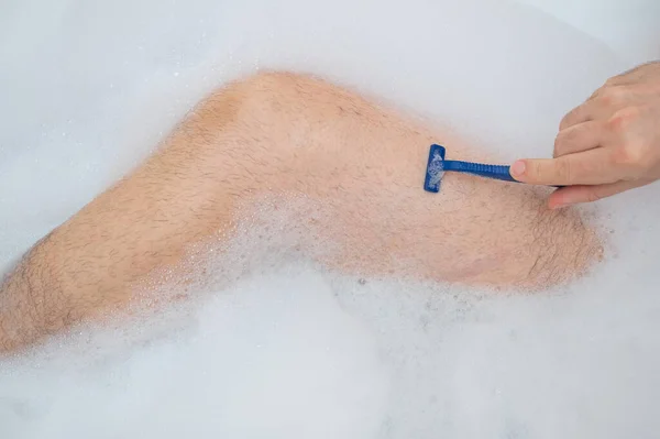 Rolig bild av en man som tar ett avslappnande bad och rakar benen. Närbild av hanfötter i ett bubbelbad. Ovanifrån. — Stockfoto