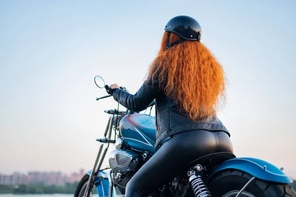 Visão traseira da mulher encaracolado ruivo no capacete na motocicleta ao ar livre. — Fotografia de Stock