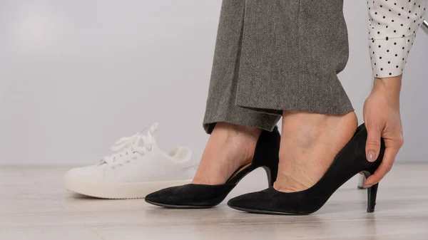 Close-up zakenvrouw neemt uit haar schoenen zet op wit lederen sneakers. — Stockfoto