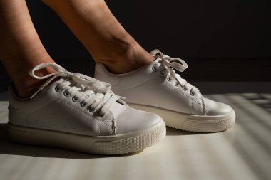 Beyaz deri ayakkabılarla kadın bacaklarının yakın çekimi..