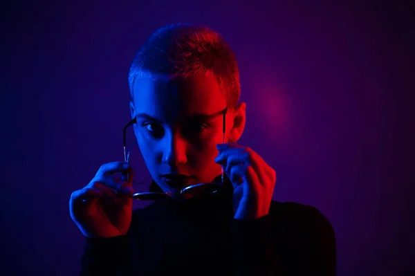 Retrato de bela jovem com cabelo curto vestindo óculos em luz de néon — Fotografia de Stock