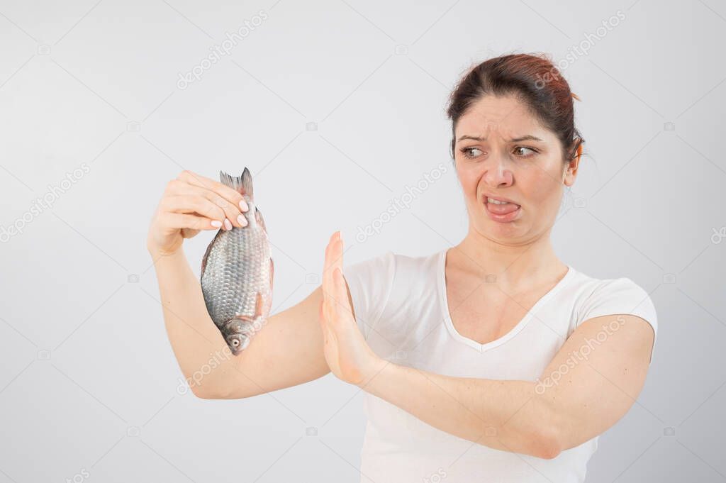 Caucasian woman opposes the disgusting smell of fish. A metaphor for womens health and intimate hygiene.