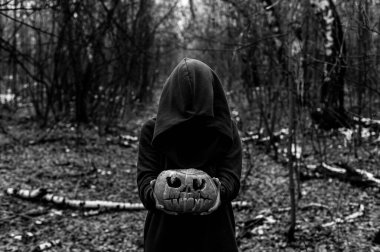 Bir cadı, yoğun bir sonbahar ormanında ürkütücü bir balkabağı tutuyor. Cadılar bayramı için fener. Tek Renkli