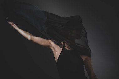 Karanlık bir stüdyoda siyah peçeli kızıl saçlı bir kadın. Burnunda küpe olan bir kız sinsice gülümsüyor. Cadı makyajı. Cadılar Bayramı kostümü.