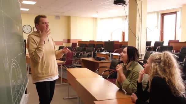 Две девушки и парень разговаривают на языке жестов. Трое глухих студентов общаются в университетском классе. — стоковое видео