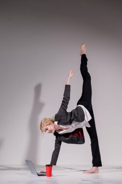 İş elbisesi giymiş çıplak ayaklı balerin dizüstü bilgisayara poz veriyor ve kahve içiyor. Bilgisayar başında esnek bir kadın çalışıyor.