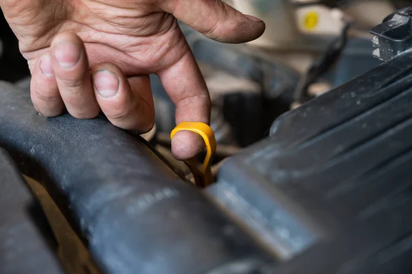 一位汽车修理工拿出一根吸盘检查汽车发动机的油位. — 图库照片