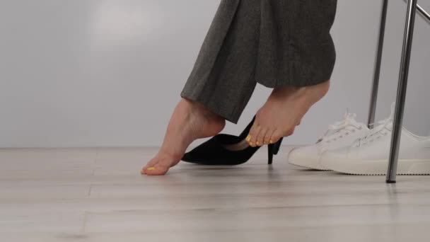 Close-up zakenvrouw neemt uit haar schoenen zet op wit lederen sneakers. — Stockvideo