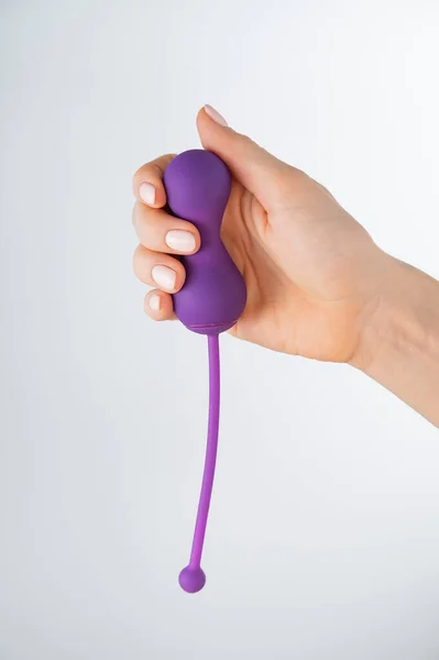 A faceless woman holding an electronic Kegel trainer for training pelvic floor muscles on a white background. Sex toy synchronized with a smartphone — Stock Photo, Image