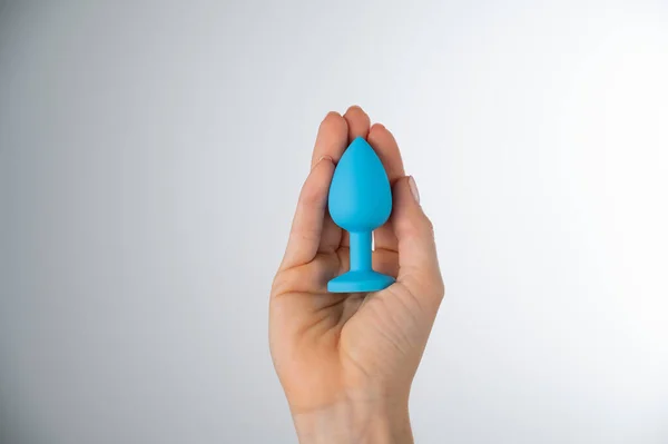 Woman holding a blue butt plug on a white background. Adult toy for alternative sex — Stock Fotó