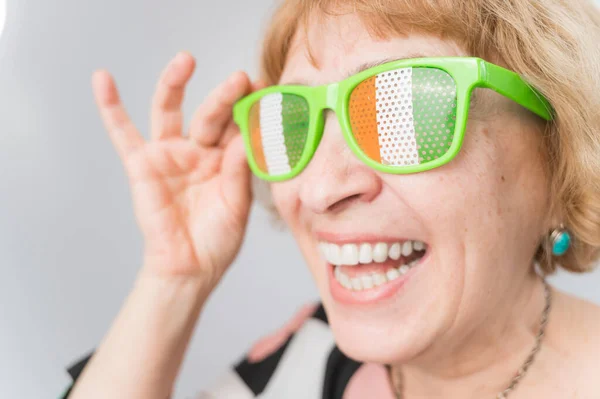 Porträtt av leende äldre kvinna bär glasögon med Irlands flagga. — Stockfoto