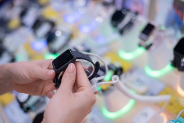 Yüzü olmayan beyaz kadın, elektronik mağazasından akıllı bir saat seçiyor.
