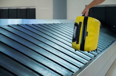 Bir kadın bagaj bandından bir bavul alır..