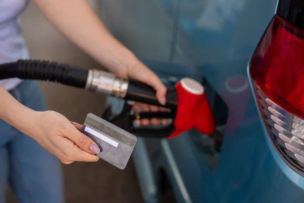 Kobieta napełnia samochód benzyną na stacji benzynowej i trzyma kartę kredytową. — Zdjęcie stockowe