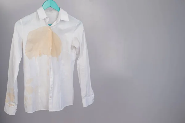 Womens office white shirt with a stain of coffee on a white background.