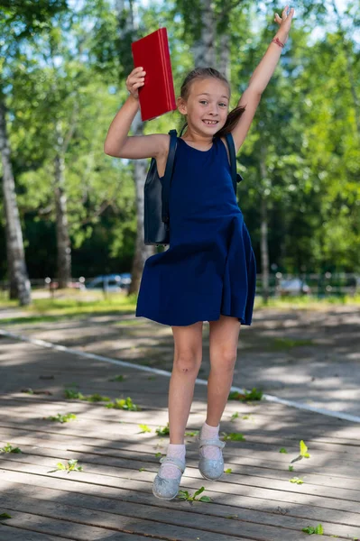 Joyful schoolmeisje springen buiten. Einde zomervakantie en begin van het basisschooljaar — Stockfoto