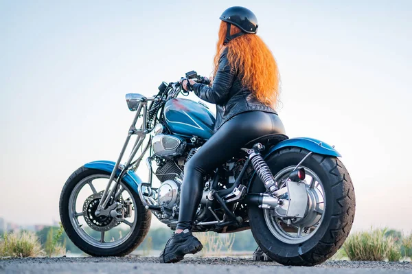 Visão traseira da mulher encaracolado ruivo no capacete na motocicleta ao ar livre. — Fotografia de Stock