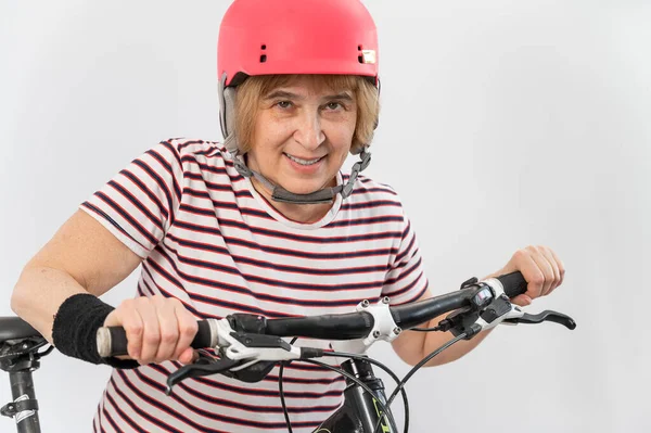 Mujer mayor con casco rosa en bicicleta sobre fondo blanco. — Foto de Stock