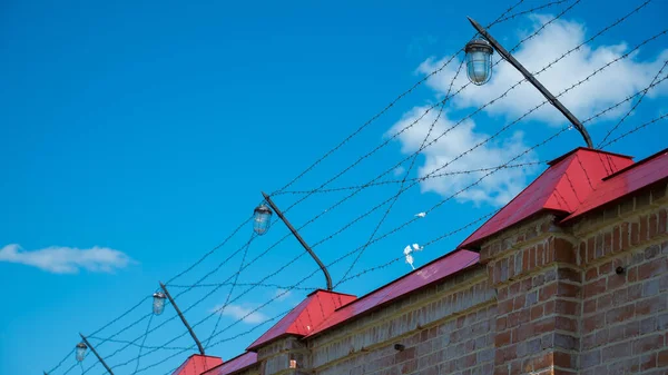 Hapishanenin çitlerinde mavi gökyüzüne karşı dikenli tel var. — Stok fotoğraf