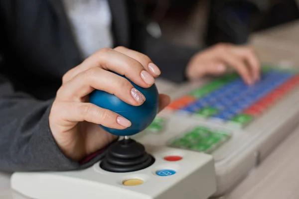 En uigenkendelig kvinde med cerebral parese skriver på tastaturet. En pige med handicap arbejder på en specielt udstyret computer - Stock-foto