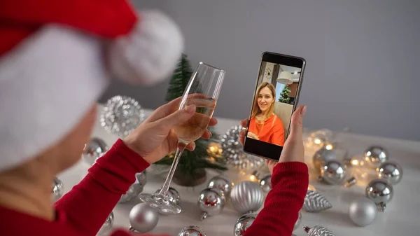 Жінки п'ють шампанське, святкують Різдво і спілкуються віддалено за допомогою смартфона. — стокове фото