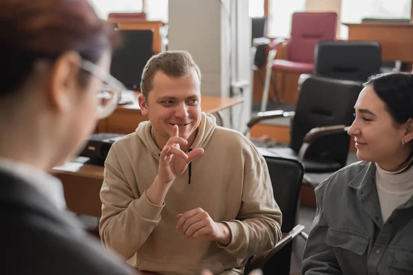 Dvě holky a chlap mluví znakovou řečí. Tři hluší studenti chatují v univerzitní třídě. — Stock fotografie