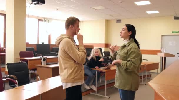 A rapariga e o tipo falam em linguagem gestual. Dois alunos surdos conversando em uma aula universitária. — Vídeo de Stock