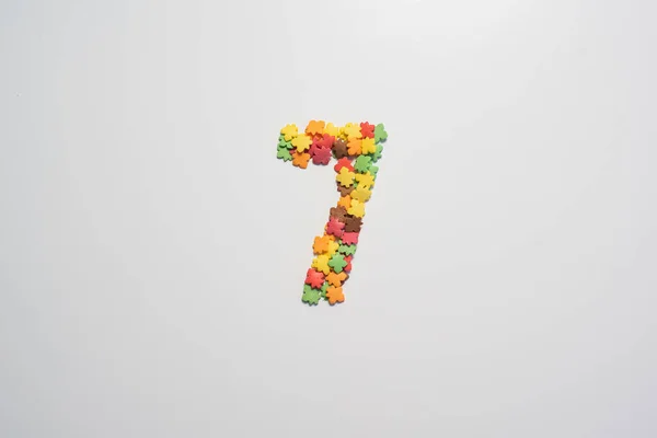 Numeral seven from sweet pastry topping in the form of colorful foliage on a white background. — Stock Photo, Image