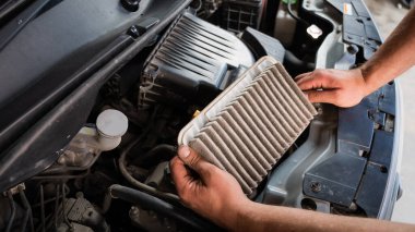 Otomobil tamircisi arabadaki hava filtresini değiştiriyor.