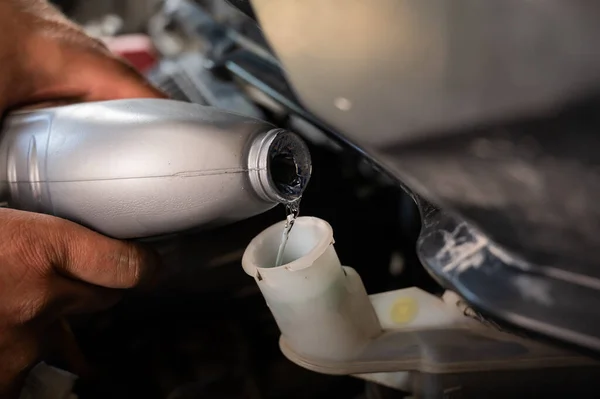 Автомеханик наливает тормозную жидкость в машину — стоковое фото